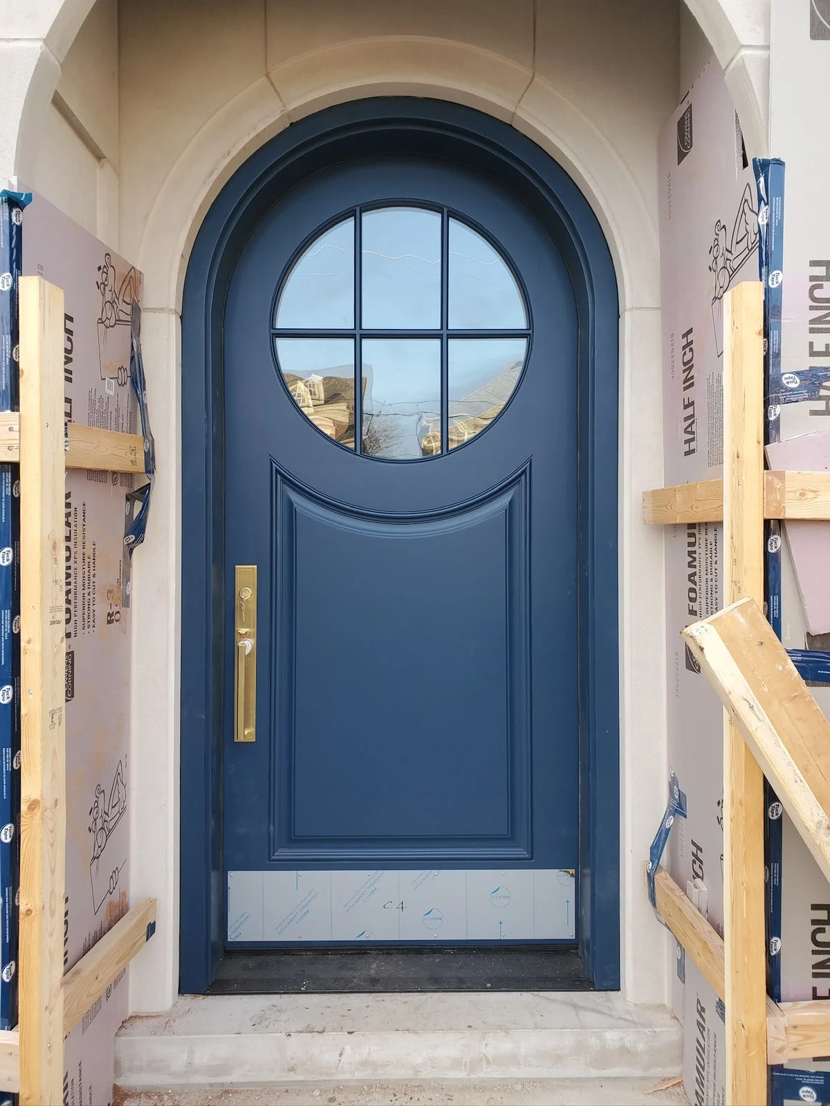 Blue arched door with round window and brass handle